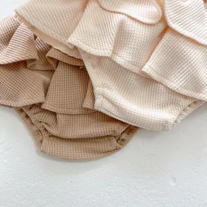 Gros plan du tissu gaufré en coton et bords à volants pour barboteuse de bébé
