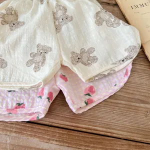 Dettaglio di pantaloncini in cotone con stampe di orsi e motivi a quadri con fragole