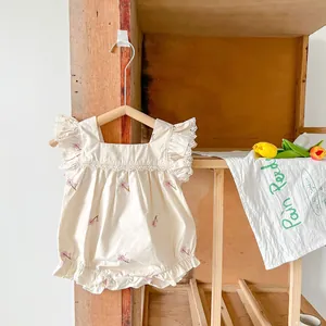 Close-up of pink flower embroidery and lace details on a baby cotton bodysuit