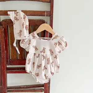 Detail of pink baby romper and hat set with vintage brown bear pattern on wooden hanger