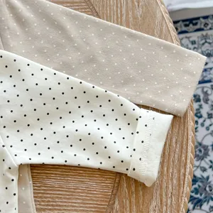 Detailed view of polka dot pattern and ribbed cuffs on cotton long sleeve baby bodysuit