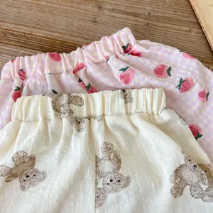 Dettaglio di pantaloncini neonato con stampe di fragole e orsetti in cotone e lino traspirante