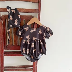 Detail of baby bear print swimsuit with matching sun hat hanging on a vintage ladder