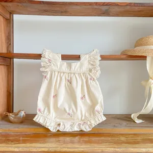 Detail of baby romper featuring delicate floral embroidery and white lace ruffle sleeves