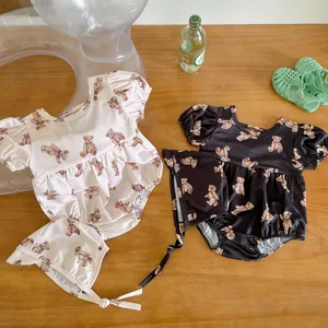 Flat lay of cute short-sleeved baby swimsuits with bear prints and matching sun hats