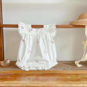 Detail of white cotton baby romper featuring delicate pink floral embroidery and lace sleeves