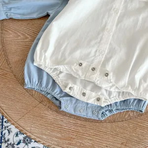 Barboteuses pour bébé en blanc et bleu clair avec détails de boutons sur table en bois