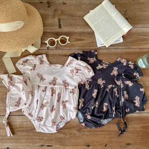 Close-up of baby girl bear print swimwear with matching hats on a wood background