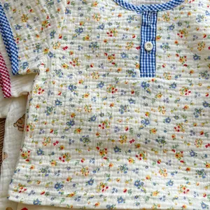 Close-up of floral seersucker baby t-shirt with blue checkered trim and white button