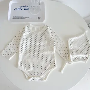 Detailed flat lay of polka dot baby romper with matching earflap hat and soft cotton texture