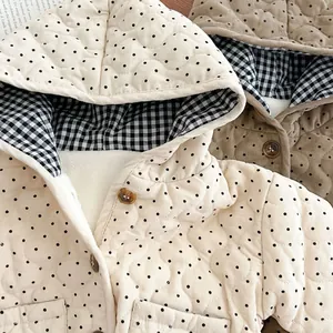 Detail of infant quilted hooded jackets with polka dots, check lining, and brown buttons