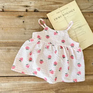 Dettaglio del tessuto seersucker con stampa fragola su un vestito rosa neonato