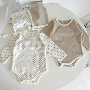 Close-up of baby bodysuits with snap closure and polka dot pattern on a white table