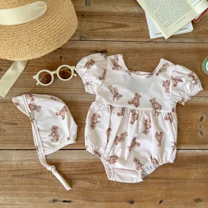 Flat lay of pink baby swimsuit with bear print, puff sleeves and matching sun hat