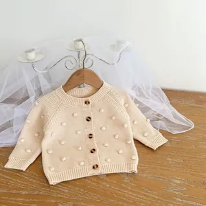 Detail of beige knit cardigan for baby girls with popcorn stitch and brown buttons