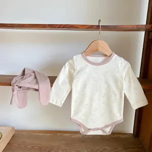 Detail of baby cotton bodysuit with rabbit print and pink ribbed trim on a hanger