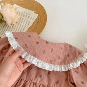 Détail d'un barboteuse pour bébé fille à fleurs avec broderie en dentelle blanche sur le col