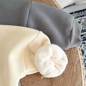 Close-up of baby dinosaur romper fabric with ribbed cuffs and soft plush ball details