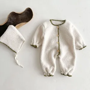 Detailed view of cream fleece baby romper with green crochet trim and wooden buttons