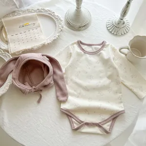 Detailed flat lay of cotton baby bodysuit set with rabbit print and bunny ear hat
