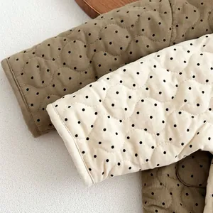 Close-up of diamond quilted corduroy fabric with black polka dots on olive green and beige
