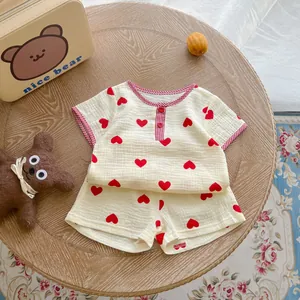 Flat lay view of a cream cotton muslin baby set with red heart prints on wooden background