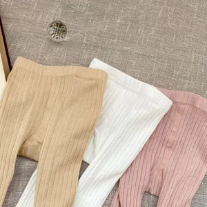 Close-up of three pairs of ribbed knit baby leggings in beige, white, and soft pink