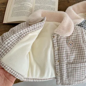 Detail of warm baby winter coat with brown plaid pattern, teddy bear embroidery and fleece lining