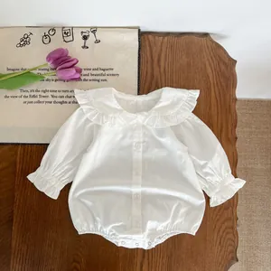 Détail d'un body bébé blanc avec col à volants et boutons sur une table en bois
