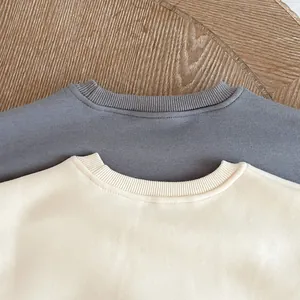 Detail of ribbed crew necklines on soft cotton baby dinosaur jumpsuits in grey and cream