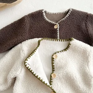 Close-up of cozy teddy fleece baby jumpsuit with wooden buttons and blanket stitch details