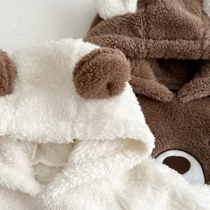 Detailed view of plush bear hooded baby jumpsuits in cream white and brown fleece texture
