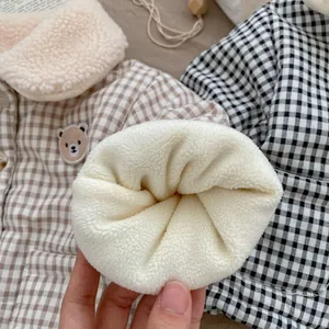 Detailed view of thick sherpa fleece lining on a checkered winter coat for toddlers