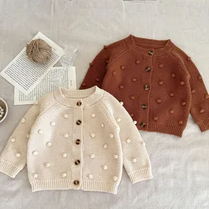 Handmade popcorn stitch baby knit cardigan in cream and rust colors with wooden buttons