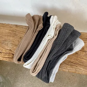 Toddler girls cable knit leggings in six colors stacked on a rustic wooden stool