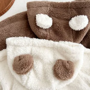 Detail of plush bear-ear hoods in brown and white lamb wool for infant rompers