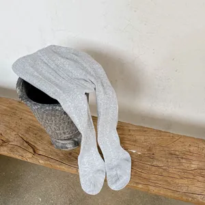 Detail of light gray ribbed knit leggings on a vintage stool with minimalist rustic background