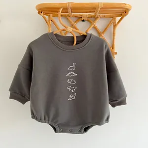 Detailed view of dark grey baby bodysuit with cute white line dinosaur prints on soft fabric