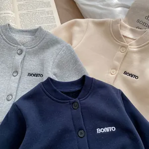 Dettaglio di cardigan per neonati in pile di cotone grigio, beige e blu navy con ricamo