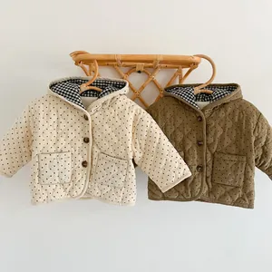Detail of infant hooded quilted jackets featuring polka dot stitching and plaid lining
