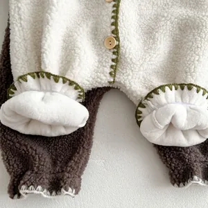 Close-up of baby sherpa romper featuring wood buttons and green crochet edge details