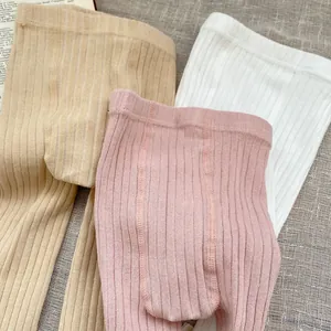 Detailed macro view of three pairs of ribbed cotton baby leggings in neutral tones