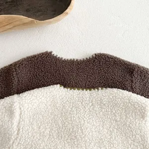 Detail of baby sherpa fleece jumpsuit showing brown and white patchwork with fine stitching