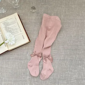 Detailed macro view of pink cotton baby tights featuring cute satin bow accents