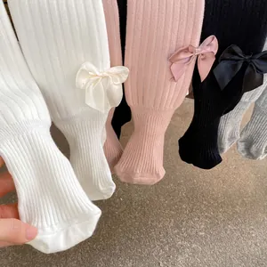 Detailed view of ribbed knit baby tights with satin bows in white, pink, grey and black