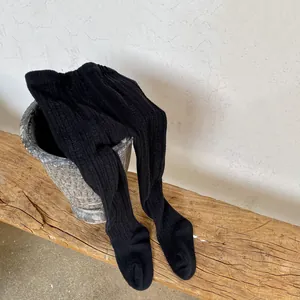 Close-up of black ribbed knit leggings showing soft cotton texture on a rustic wooden bench