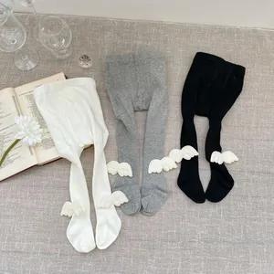 Detailed knit texture of baby leggings in white, gray, and black with angel wing accents