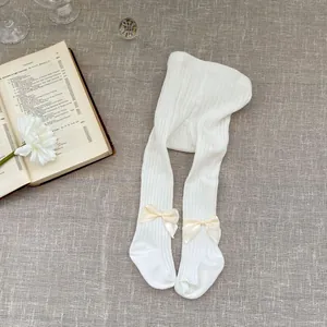 White cotton knit baby tights with vertical ribbed texture and silk bow accents