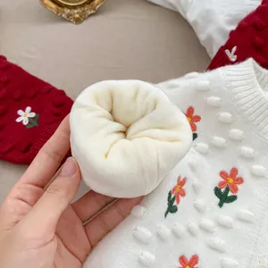 Detalle de cárdigan de punto blanco con bordados florales y forro de vellón cálido