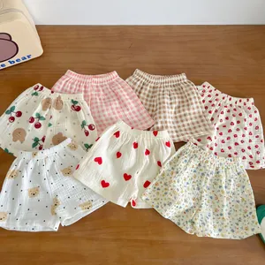 Flat lay of seven assorted prints baby cotton gauze shorts on wooden surface